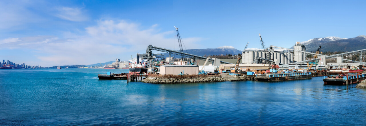 Harbor port industry with view of downtown cityscape on sunny day. Panorama of marine industry, grain terminal with elevator and silos. North Vancouver port with view of Vancouver. Selective focus.
