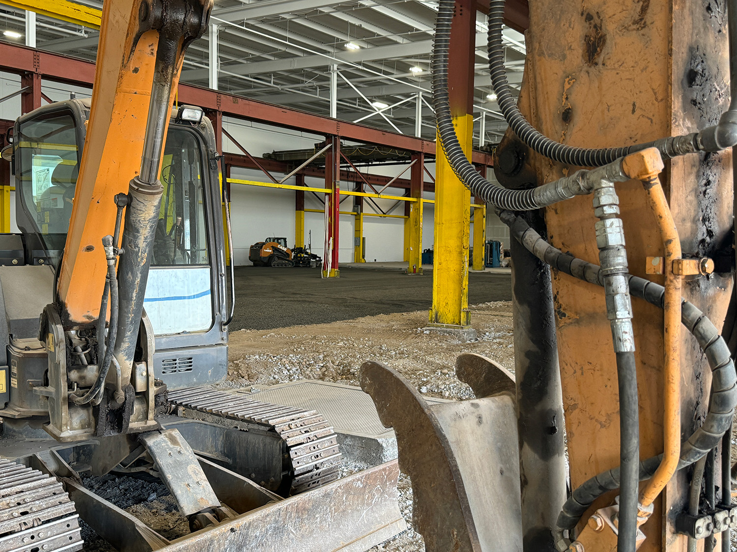 An excavator and grader preparing the base for concrete.